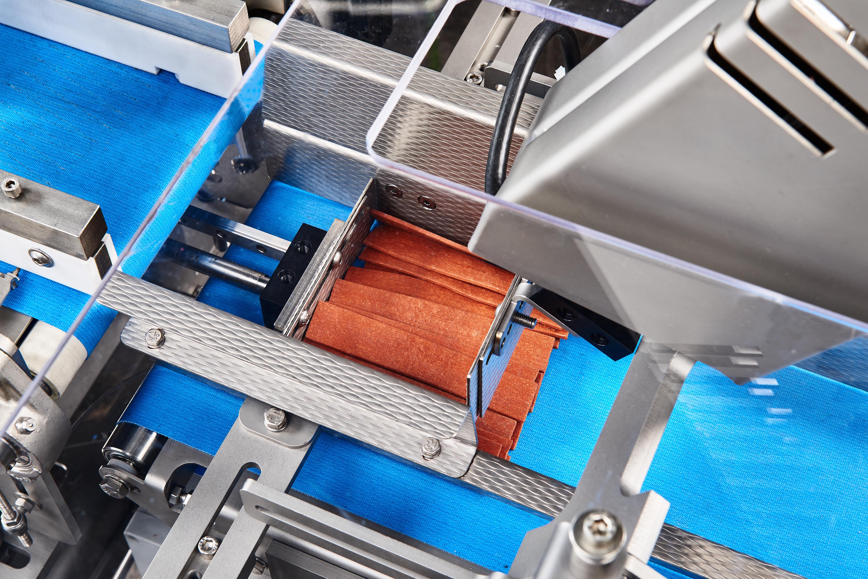 Chewing strip merging with telescopic discharge and Linmot step feeder