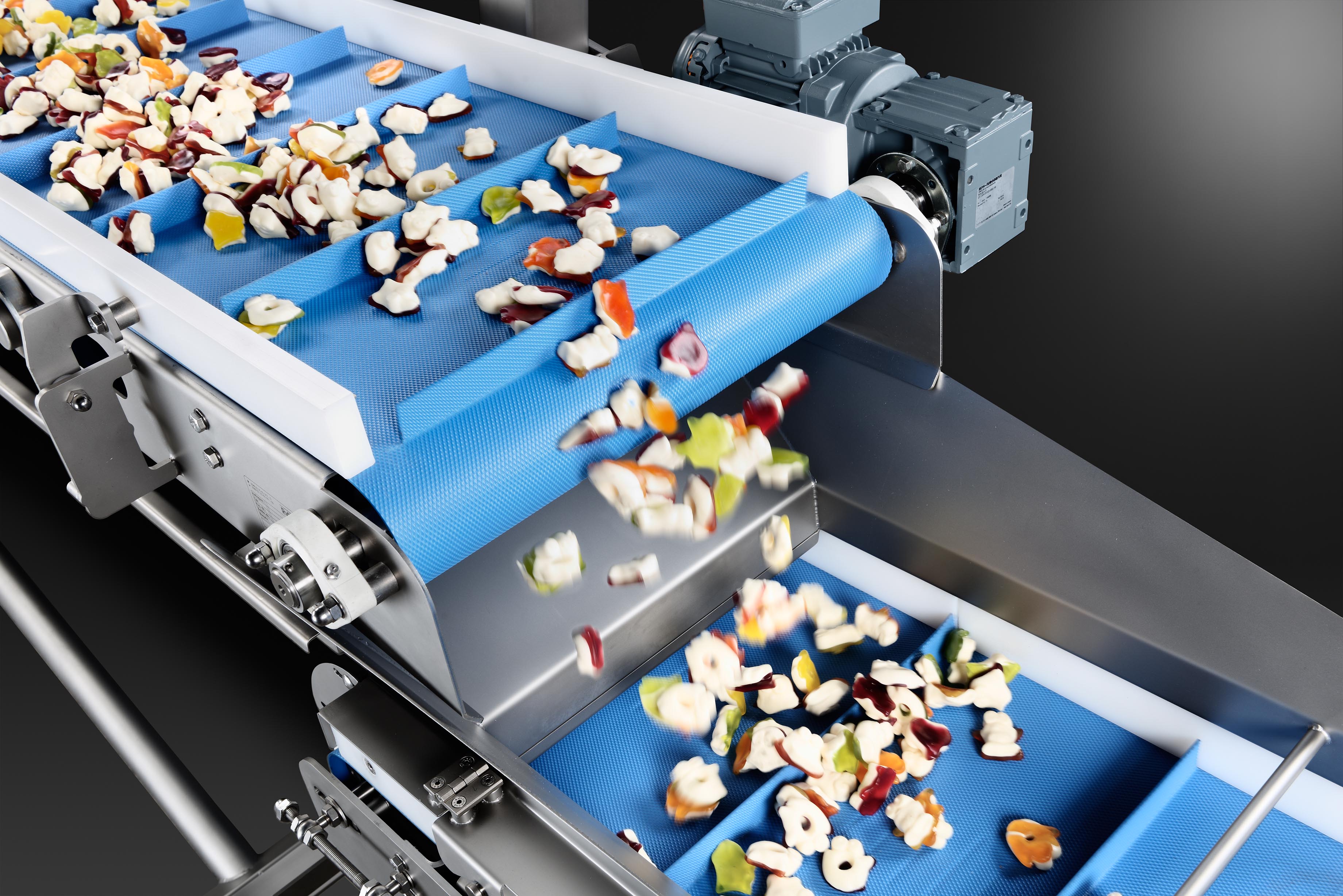 Cleated belt conveyor with fabricless belt for transporting mogul goods or fruit gums